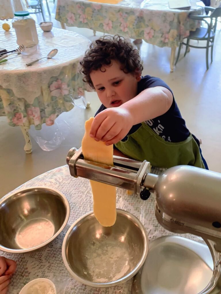 A little boy carefully flattens his dough on Italian cooking class day