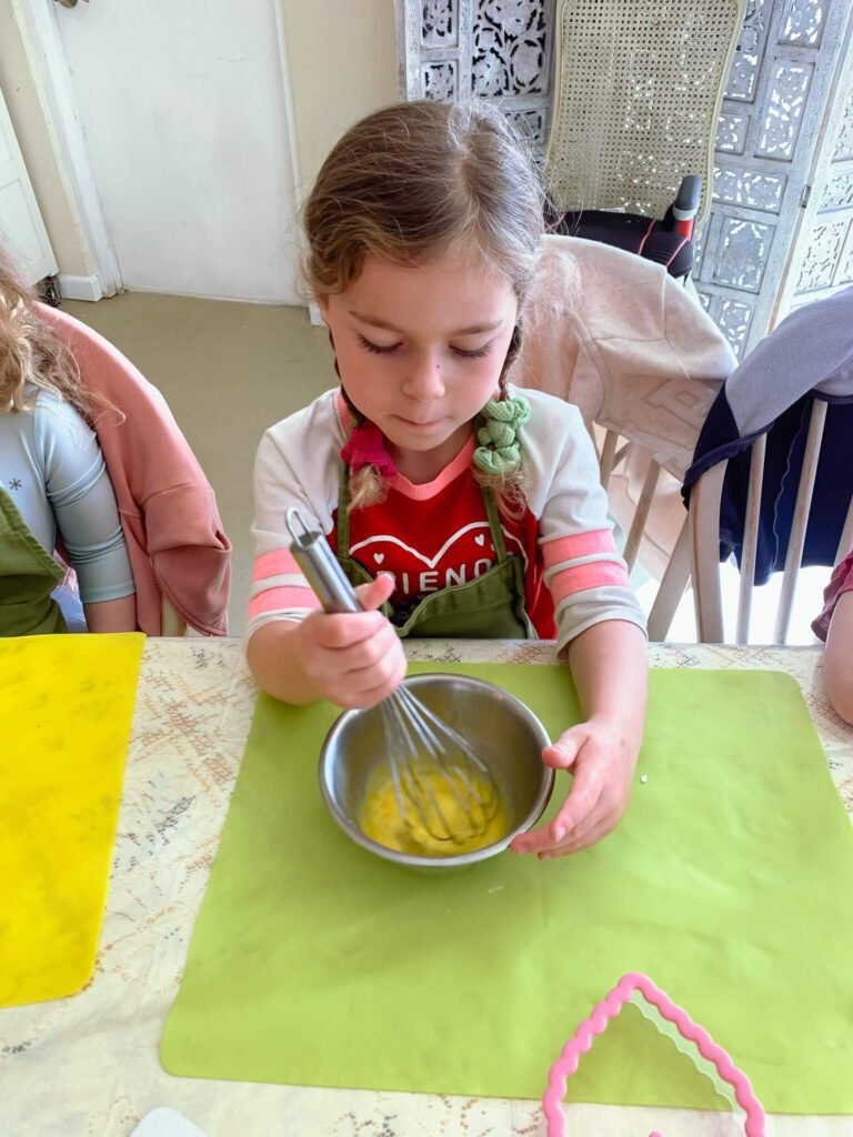 A little girl preps eggs for her dough